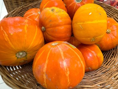 Villach, Avusturya - 30 Temmuz 2025: Canlı turuncu balkabakları, pürüzsüz yüzeylerini ve mevsimsel cazibelerini vurgulayan bir sepetin içinde istiflenmiştir.