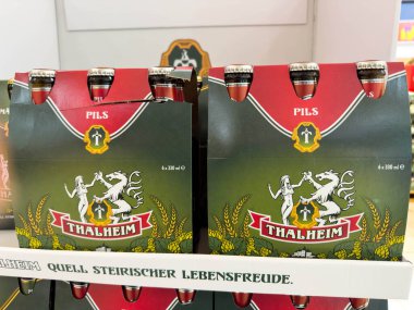 Villach, Avusturya - 30 Temmuz 2025: Thalheim Pils birası bir perakende satış ortamında belirgin bir şekilde sergileniyor, cazip paketleme ve markalaşmasını vurguluyor