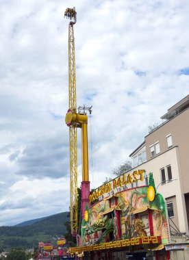 Villach, Avusturya - 30 Temmuz 2025: Eğlence parkı gezisi heyecan ve macera dolu heyecan verici bir atmosfer yaratarak, renkli bir cazibenin üzerinde yükseliyor
