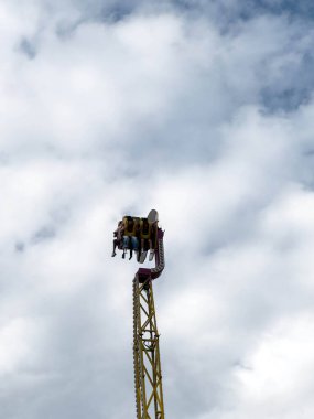 Villach, Avusturya - 30 Temmuz 2025: Eğlence parkı gezisi, dramatik bulutlarla çevrili, heyecan verici bir atmosfer yaratarak, heyecan verici yolcuları gökyüzüne çıkardı.