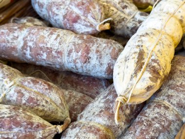 Pazar vitrininde beyaz küf ve ip bağları olan iyileşmiş salam sosislerinin çeşitliliği.