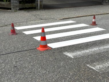 Asfalt yolda trafik konileriyle yaya geçidi.