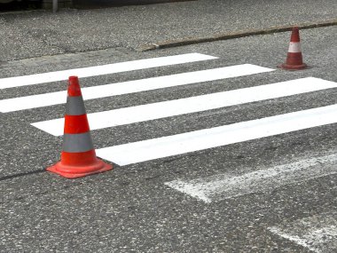 Boş yaya geçidi ve asfalt yolda trafik konileri var..