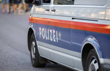 Velden, Avusturya - 18 Haziran 2025: POLİZEI harflerini gösteren polis aracı şehir merkezinde yayalar eşliğinde sokağa park edildi