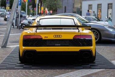 Velden, Avusturya - 18 Haziran 2025: Aerodinamik tasarımı ve lüks cazibesini vurgulayarak, Sportwagenfestival sırasında kaldırım taşı caddesinde açık sarı renkli Audi R8 park etti.