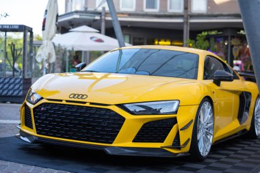Velden, Avusturya - 18 Haziran 2025: Audi R8 bir festivalde park etmiş parlak sarı renkte, parlak çizgileri ve modern tasarımı kentsel bir ortama karşı vurguluyor
