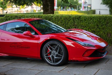 Velden, Avusturya - 18 Haziran 2025: Kırmızı Ferrari spor arabası Sportwagenfestival 'de canlı yeşilliğin yanına park edilmiş, çarpıcı tasarımı ve işçiliği vurgulanıyor