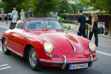 Velden, Avusturya - 18 Haziran 2025: Sportwagenfestival 'da üstü açık kırmızı Porsche 356 sürüş, etkinliğin keyfini çıkaran coşkulu izleyicilerle çevrili