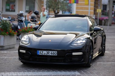 Velden, Avusturya - 18 Haziran 2025: Siyah Porsche Panamera, Sportwagenfestival sırasında lüks ve otomotiv işçiliğini ön plana çıkaran canlı bir caddeye park etti