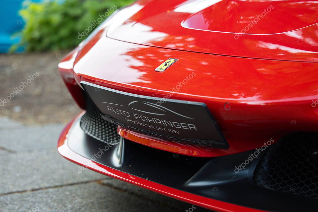 Velden, Austria - June 18, 2025: Front view of a red Ferrari sports car at Sportwagenfestival, emphasizing its sleek design and iconic logo with vibrant surroundings