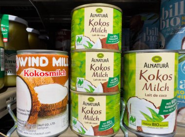 Villach, Avusturya - 15 Ağustos 2025: Konserve Alnatura ve Windmill hindistan cevizi sütü süpermarketin rafında, organik içecek seçeneklerini vurguluyor