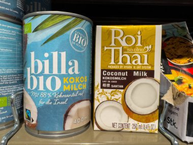 Villach, Avusturya - 15 Ağustos 2025: Billa biyolojisinden hindistan cevizi sütü kutuları ve Roi Thai markaları, organik ve geleneksel seçenekleri ön plana çıkaran bir market rafına yerleştirilmiştir.