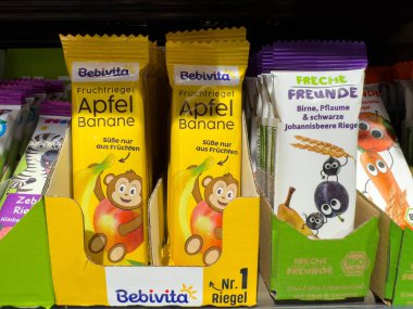 Villach, Avusturya - 15 Ağustos 2025: Rafta elma ve muz aromalı Bebivita meyve barları, renkli ambalajlar ve eğlenceli maymun karakter tasarımı