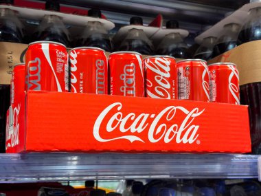 Villach, Avusturya - 15 Ağustos 2025: Coca-Cola kutuları tanıtılabilir marka ve tanıtım amaçlı kullanım için canlı kırmızı renkleri vurguluyor