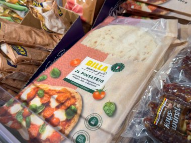 Villach, Avusturya - 15 Ağustos 2025: BILLA pizza hamur ambalajı bir marketin dondurucusunda belirgin bir şekilde sunuluyor, taze malzemeler ve çekici tasarım ön plana çıkıyor
