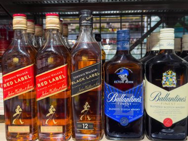 Villach, Avusturya - 15 Ağustos 2025: Johnnie Walker Red Label ve Black Label, Ballantine 'ın en iyi viski şişeleri perakende satış rafında sergileniyor.