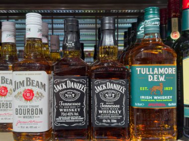 Villach, Avusturya - 15 Ağustos 2025: Jim Beam, Jack Daniel 's ve Tullamore D.E.W. İçki dükkanındaki bir rafta ayarlanmış viski.