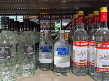 Villach, Avusturya - 15 Ağustos 2025: Votka şişeleri, Absolut Votka ve Stolichnaya markalarının benzersiz ambalajları eşliğinde bir süpermarket rafında düzenlenmiştir.