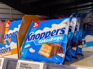 Villach, Avusturya - 15 Ağustos 2025: Knoppers Kokosriegel çikolataları bir süpermarket rafına güzelce yerleştirilmiş, çekici ambalajlarını ve çekici cazibelerini vurguluyorlar