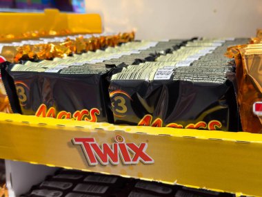 Villach, Avusturya - 15 Ağustos 2025: Twix çikolataları perakende satış ortamında canlı sarı bir rafta düzenlenmiş, popüler şeker seçeneklerini vurguluyor