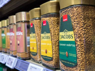 Villach, Avusturya - 15 Ağustos 2025: Jacobs kahve kavanozları farklı aromalar ve canlı ambalaj tasarımları içeren bir süpermarket rafına yerleştirildi