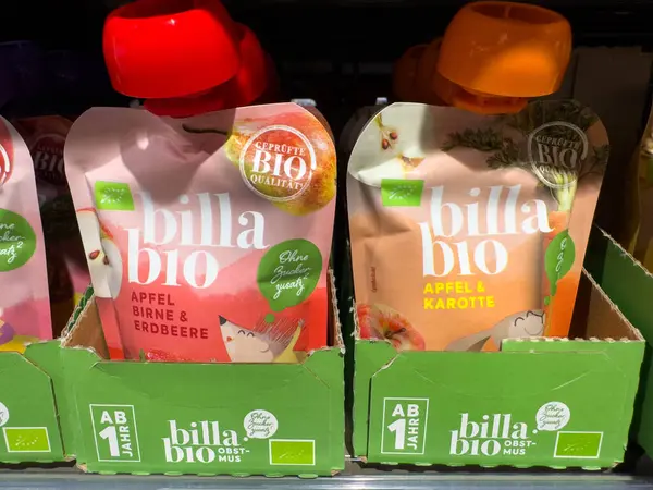 Villach, Avusturya - 15 Ağustos 2025: Elma, armut ve havuç aromalı biyo-meyve paketleri, düzgünce bir süpermarket rafında dizilmiş