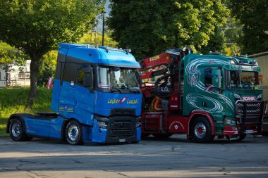 Faak Am See, Avusturya - 09 Ağustos 2025: Renkli mavi ve yeşil kamyonlar taşıyan kamyoncular Faak Gölü yakınlarında 1.4 numaralı görevde birlik ve dostluğu kutluyorlar