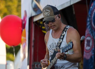 Faak Am See, Avusturya - 09 Ağustos 2025: Gitarist, renkli dekorasyonlar ve canlı atmosferle çevrili açık hava etkinliklerinde seyirciyi cezbetti