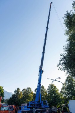 Faak Am See, Avusturya - 09 Ağustos 2025: Mavi vinç açık gökyüzünün altında duruyor ve Faak Gölü 'ndeki Oyuncak Ayı Misyonu sırasında neler yapabileceğini gösteriyor