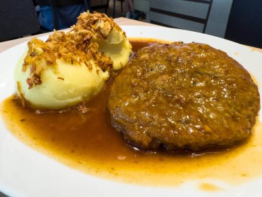 Sos soslu lezzetli köfte ve çıtır soğanla süslenmiş patates püresi..