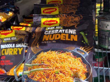 Villach, Avusturya - 18 Ağustos 2025: Maggi Magic Asia kızarmış erişte ambalajı açık bir süpermarket rafında, parlak renkler ve çekici grafiklerle gösteriliyor