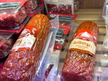 Villach, Avusturya - 18 Ağustos 2025: Dilimlenmiş Hofstadter sosisleri bir şarküteride güzelce düzenlenmiştir, zengin renklerini ve çekici ambalajlarını vurgularlar