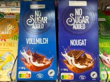 Villach, Avusturya - 18 Ağustos 2025: Frankonia 'da rafa çikolata eklenmedi, Vollmilch ve Nougat aromalı canlı ambalajlar sergilendi