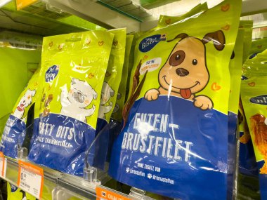 Villach, Avusturya - 18 Ağustos 2025: Köpek maması paketleri süpermarket raflarında sergileniyor, evcil hayvan severler için parlak renkler ve eğlenceli resimler sergileniyor
