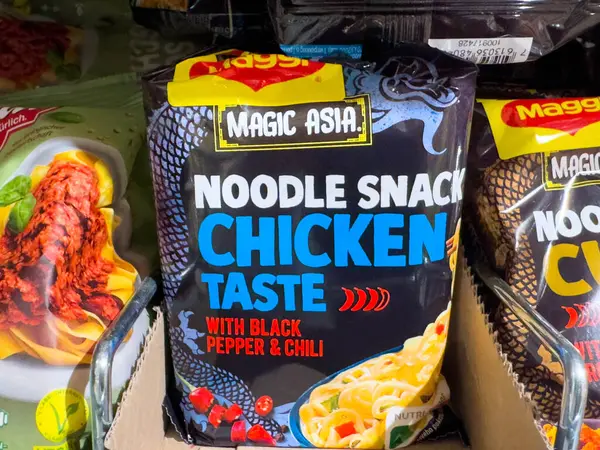 Villach, Avusturya - 18 Ağustos 2025: Sihirli Asya erişte çerez paketi tavuk aromasını siyah biber ve kırmızı biberli, göz alıcı tasarım ve renklerle ön plana çıkarıyor