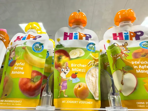 Villach, Avusturya - 18 Ağustos 2025: HiPP organik bebek maması kesesi rengarenk bir süpermarket rafında elma, armut, muz ve müsli aromaları sergiliyor