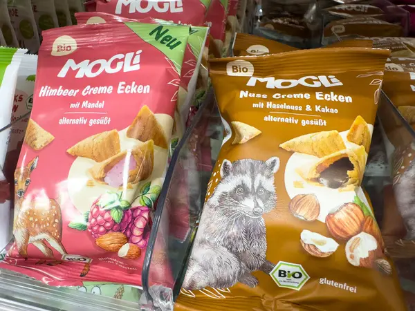 Villach, Avusturya - 18 Ağustos 2025: Ahududu ve fındık kremalı MOGLI abur cubur paketleri, açık renkli bir market koridorunda belirgin bir şekilde sergilenmektedir
