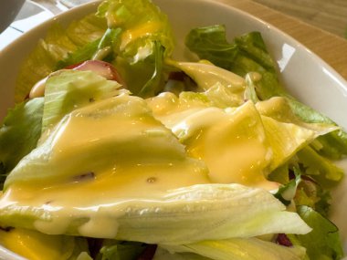 Taze yeşil salata, kremalı sos ve beyaz kâse..