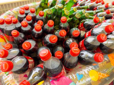 Klagenfurt, Avusturya - 20 Ağustos 2025: Coca-Cola ve yeşil soda şişeleri, yaz etkinlikleri için mükemmel, renkli bir şekilde düzenlenmiştir