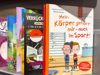 Klagenfurt, Avusturya - 20 Ağustos 2025: Çocuklar için spor ve beden farkındalığı konulu eğlenceli illüstrasyonlar ve temalar içeren parlak renkli çocuk kitapları raflarda sergileniyor