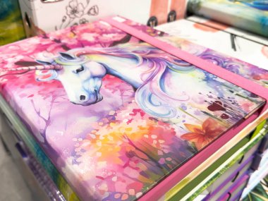 Klagenfurt, Avusturya - 20 Ağustos 2025: Canlı çiçek desenleriyle defter kapağındaki tuhaf tek boynuzlu at illüstrasyonu, sanatsal yaratıcılık ve cazibeyi yakalıyor