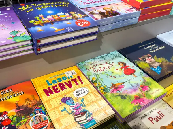 Klagenfurt, Avusturya - 20 Ağustos 2025: Parlak kapaklı ve resimli çocuk kitapları, bir kitapçının rafında düzgünce düzenlenmiştir