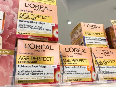 Villach, Avusturya - 21 Ağustos 2025: L 'Oreal Paris Çağı Kusursuz Altın Çağ cilt ürünleri perakende satış ortamında raflarda düzenlenerek canlı ambalajlarını vurguluyor