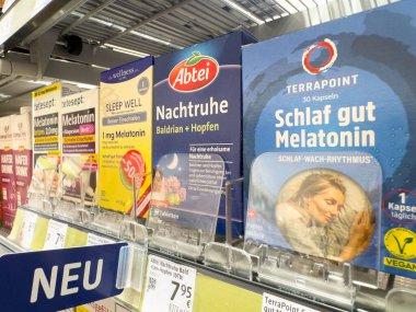 Villach, Avusturya - 21 Ağustos 2025: Melatonin ürünleri eczane raflarında çeşitli markalar ve renkli ambalajlar, uyku sağlığı ve rahatlamayı teşvik eden ürünler