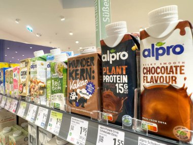 Villach, Avusturya - 21 Ağustos 2025: Alpro bitkisel içecekler, çikolata aromalı ve protein seçeneklerini ön plana çıkaran bir süpermarket rafında düzenli olarak düzenlenir