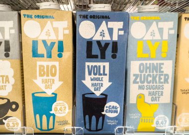 Villach, Avusturya - 21 Ağustos 2025: Rafa dizilmiş yulaflı süt kutuları, farklı tatlar ve canlı ambalajlar, bitki temelli besinlerin teşvik edilmesi