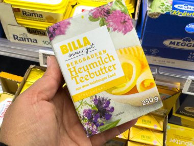 Villach, Avusturya - 21 Ağustos 2025: BILLA Heumilch Teebutter paketi, bakkal ortamında renkli çiçek tasarımı ve tereyağı ürünlerinin altını çizerek elde sergilenmektedir