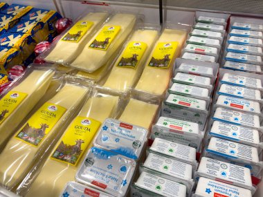 Villach, Avusturya - 21 Ağustos 2025: Gouda peyniri ve yumurtaları, taze süt ürünleri ve renkli ambalajları ön plana çıkaran bir süpermarket dondurucusunda düzgünce düzenlenmiştir.