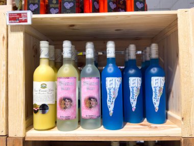 Villach, Avusturya - 21 Ağustos 2025: Ahşap rafta çeşitli şişelenmiş içecekler, canlı renkler ve eşsiz tatlar sergileniyor, yaz toplantıları ve kutlamalar için mükemmel