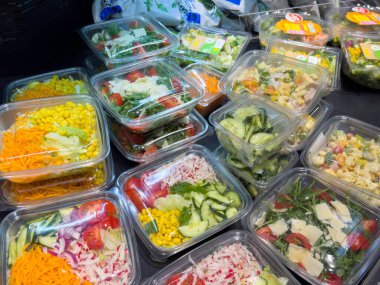 Villach, Avusturya - 21 Ağustos 2025: Canlı sebzeler ve sağlıklı yemek seçeneklerini ön plana çıkaran temiz kaplarda çeşitli taze salatalar